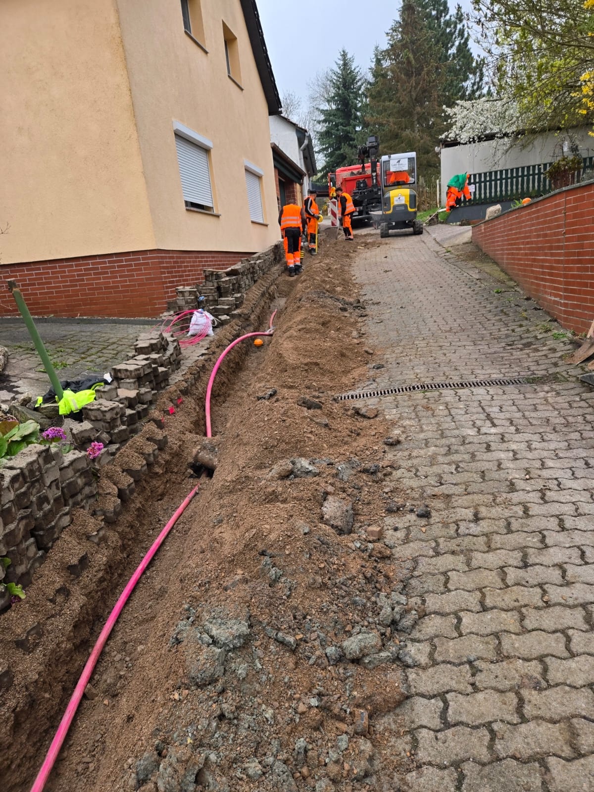 Glasfaser-Hausanschluss mit Minibagger in einer Einfahrt